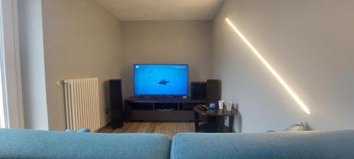 a living room with a blue couch and a flat screen tv at Il Profumo Dellegrazie in Le Grazie