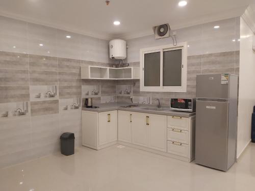 a kitchen with white cabinets and a sink and a refrigerator at شقق فلورنيسا الفندقيه in Taif