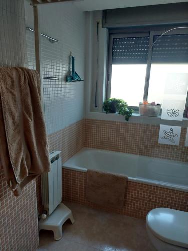 baño con bañera, ventana y lavamanos en Triplex, en Palamós