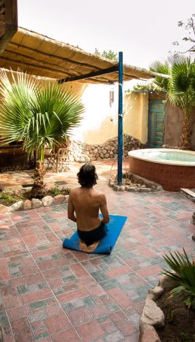 a man sitting on a blue mat in a courtyard at Villa Boheme & Atelier Boheme in Dahab