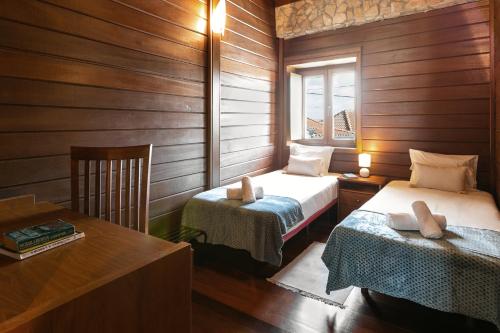 two beds in a room with wooden walls and a table at Stylish Rustic Villa in Vau