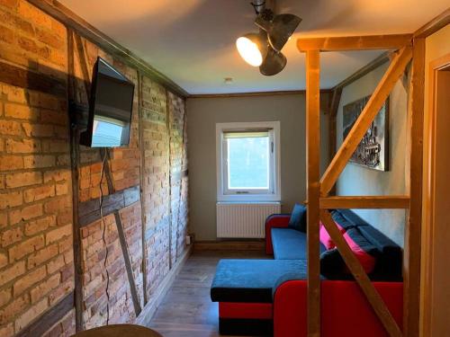 a living room with a brick wall and a tv at Wellness & Wirlpool-Oase am Wald - Waldferienhaus Dunja in Oybin in Hain