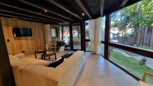 a living room with a couch and a large window at Haus del Arroyo - Andarlibre in San Martín de los Andes