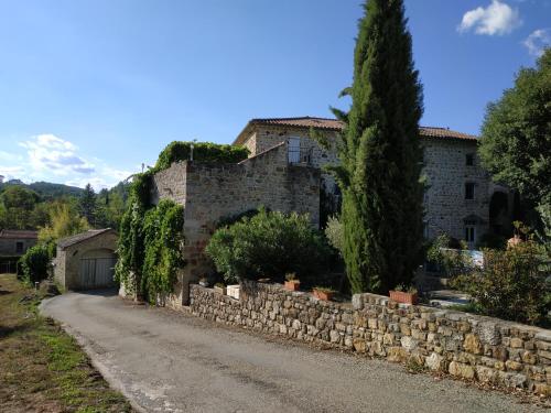 a stone house with a stone wall and a road at La musardière in Les Assions