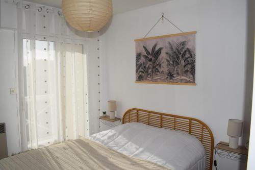 een slaapkamer met een bed en een foto aan de muur bij Côte et Vie - appartement et garage in Saint-Gilles-Croix-de-Vie