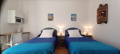 two beds in a room with blue sheets at Chambres d'hôtes La Gardie in Vias