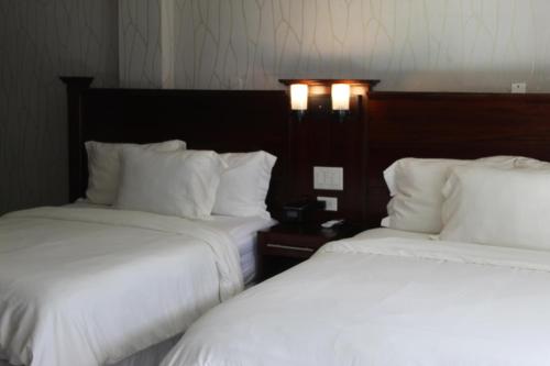 two beds in a hotel room with white sheets at Barefoot Caye Caulker Hotel in Caye Caulker