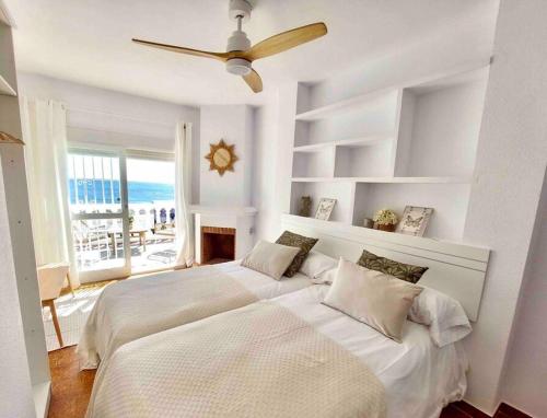 Habitación blanca con 2 camas y ventilador de techo. en Caleta Beach House Villa Beatriz Sinese Design, en Torre del Mar