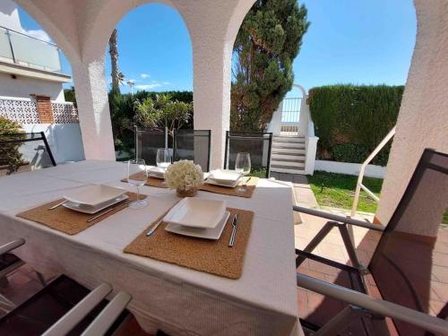 una mesa blanca con platos y vasos en el patio en Caleta Beach House Villa Beatriz Sinese Design en Torre del Mar