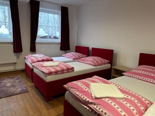 drie bedden in een kamer met rode en witte lakens bij Pension u Vlčků in Hracholusky