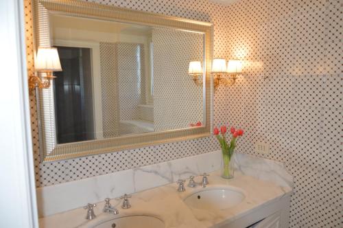 baño con lavabo, espejo y flores en Le stanze dei Mori - quadrupla con bagno privato en Mascalucia