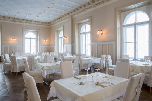 a dining room with white tables and white chairs at Maloja Palace Suites CO2-Neutral in Maloja