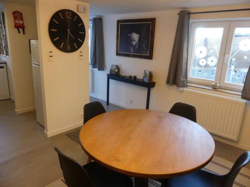a dining room with a table and a clock on the wall at La tanière des oursons in Aywaille