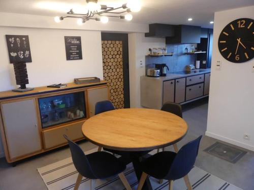 a kitchen with a table and chairs and a clock at La tanière des oursons in Aywaille