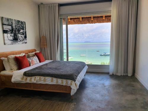 a bedroom with a large window with a view of the ocean at Luxury beachfront villa with private pool - Jolly's Rock in Calodyne