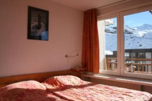 een slaapkamer met een bed en een groot raam bij Appartement 45m2 - 7 personnes - exposition sud in Val Thorens