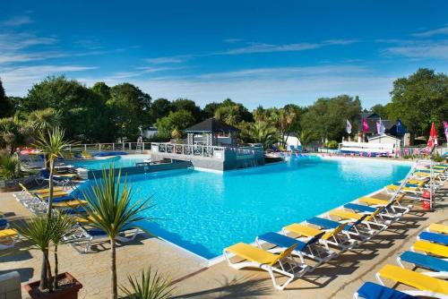 une grande piscine avec des chaises longues et un complexe hôtelier dans l'établissement mobil-home 4/6 pers, à Pont-Aven