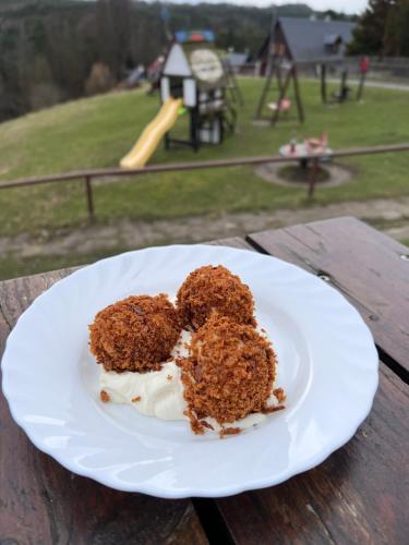 a piece of cake on a plate on a table with a playground at Resort Mezná in Hřensko