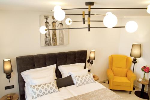 a bedroom with a bed and a yellow chair at Afrodita Wellness Essence in Plitvička Jezera