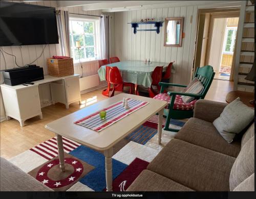 uma sala de estar com uma mesa e algumas cadeiras em Sørlandshus i skjærgården Anneks em Grimstad