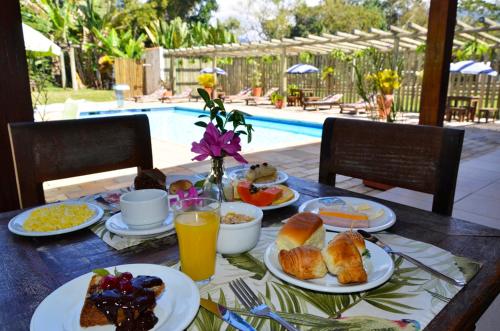 a table with breakfast foods and drinks and a pool at Hotel Bertell in Penedo