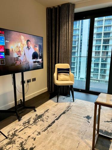 a living room with a flat screen tv and a chair at Staycity One Bedroom Luxury Apartment in London