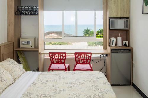 two red chairs in a bedroom with a bed and a window at Apartamento Ganem 505a in Cartagena de Indias