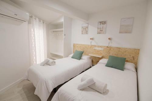 2 letti in una camera con pareti bianche e cuscini verdi di Apartamentos Turísticos A Tu Verita a Jaraiz de la Vera