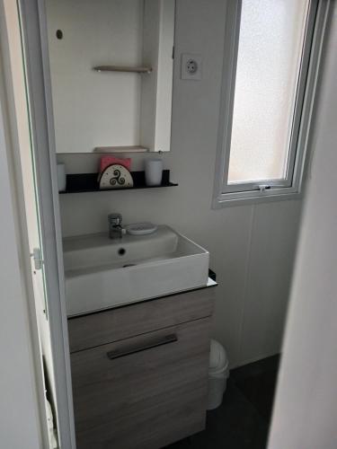 y baño con lavabo y espejo. en Mobil home 4-6 places St brėvin les pins 44, en Saint-Brevin-les-Pins