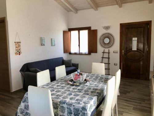 a dining room table with white chairs and a blue couch at casa indipendente con accesso diretto al mare in Ovile la Marina