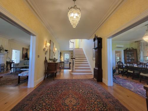 a living room with a staircase and a chandelier at Hornsby House Inn in Yorktown