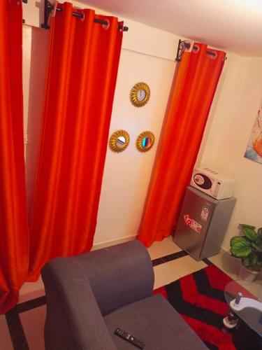 een woonkamer met oranje gordijnen en een stoel bij Triad apartments in Nairobi