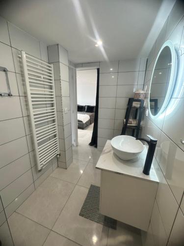 La salle de bains blanche est pourvue d'un lavabo et d'un miroir. dans l'établissement Joli appartement au calme avec place de parking privé, à Saint-Jean-Bonnefonds