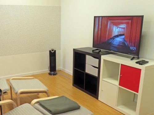 a living room with a flat screen tv on a cabinet at Bakkegata - The blue House in Odda