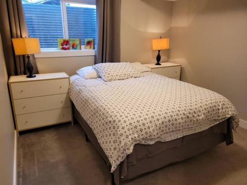 a bedroom with a bed with two night stands and two lamps at Lakeview in Peachland