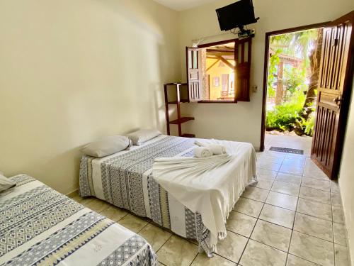 a bedroom with two beds and a tv on the wall at Pousada Aruanã in Arraial d'Ajuda