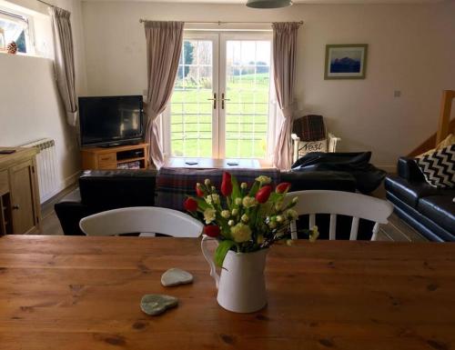 wazon kwiatów na drewnianym stole w salonie w obiekcie Wonderful rural dwelling- relax or explore Kent! w mieście Kent