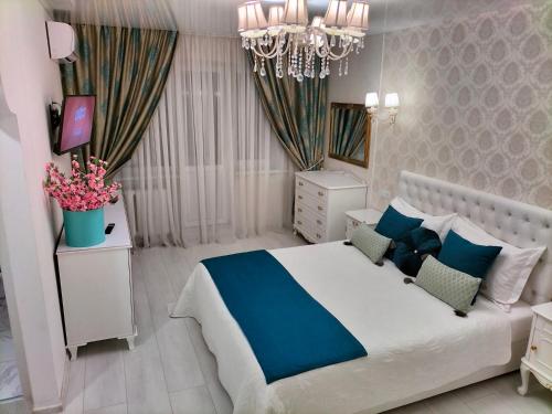 a white and blue bedroom with a bed and a chandelier at VIP Апартаменти in Dnipro