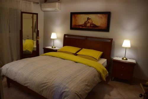 a bedroom with a bed with yellow sheets and two lamps at Βίλα Εύη in Lygourio