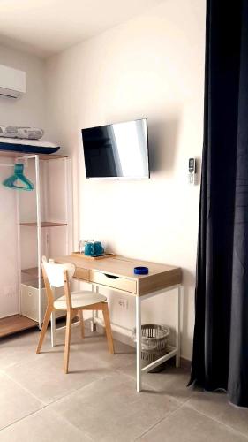 a desk with a chair and a television on a wall at Casa Villaggio Pirandello in Agrigento