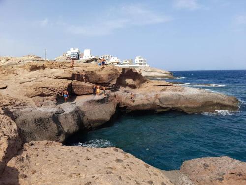 a group of people standing on the rocks near the ocean at CASA CORALES in La Mareta