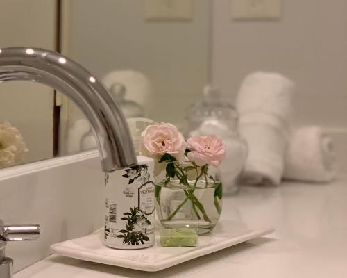 a sink with two pink roses in a vase at Soar Luxury Studio en el centro de Salta in Salta