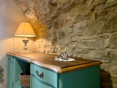 a table with a lamp and a stone wall at Habitaciones rurales en Colomers in Colomés