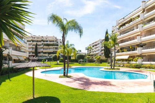 un apartamento con piscina y palmeras en Apartamento con espectaculares vistas al Golf en Marbella - Xallas 2 3, en Marbella