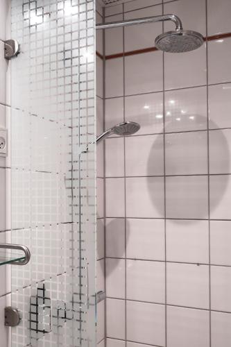 a bathroom with a shower with white tile at Hotel Alexandra in Copenhagen
