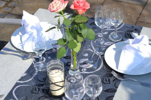 a table with glasses and a vase with flowers on it at Hotel-Restaurant Heiligenstadter Hof in Heiligenstadt