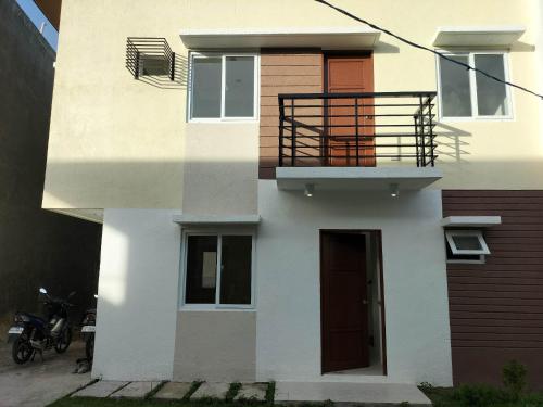 a white building with a balcony and a door at House in Philippines in Liloan