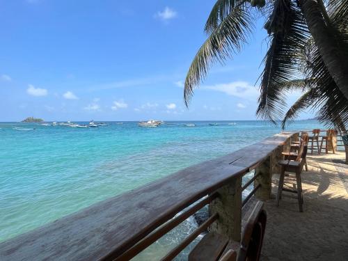 a wooden boardwalk on a beach with chairs and the ocean at Hotel Katamaran in Capurganá