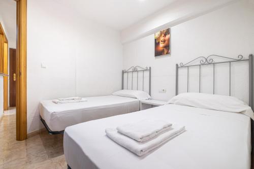 ベニドルムにあるCarabelas II 6-2の白いシーツが備わるベッド2台が備わる客室です。