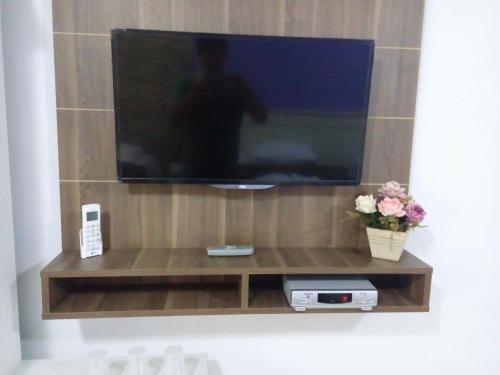 TV de pantalla plana en la parte superior de una estantería de madera en Pousada Cantinho, en Gramado